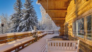 A wooden deck with benches and a swing, surrounded by snow-covered trees. - Explore Fairbanks! Authentic Log Cabin w/ Views (Fairbanks)