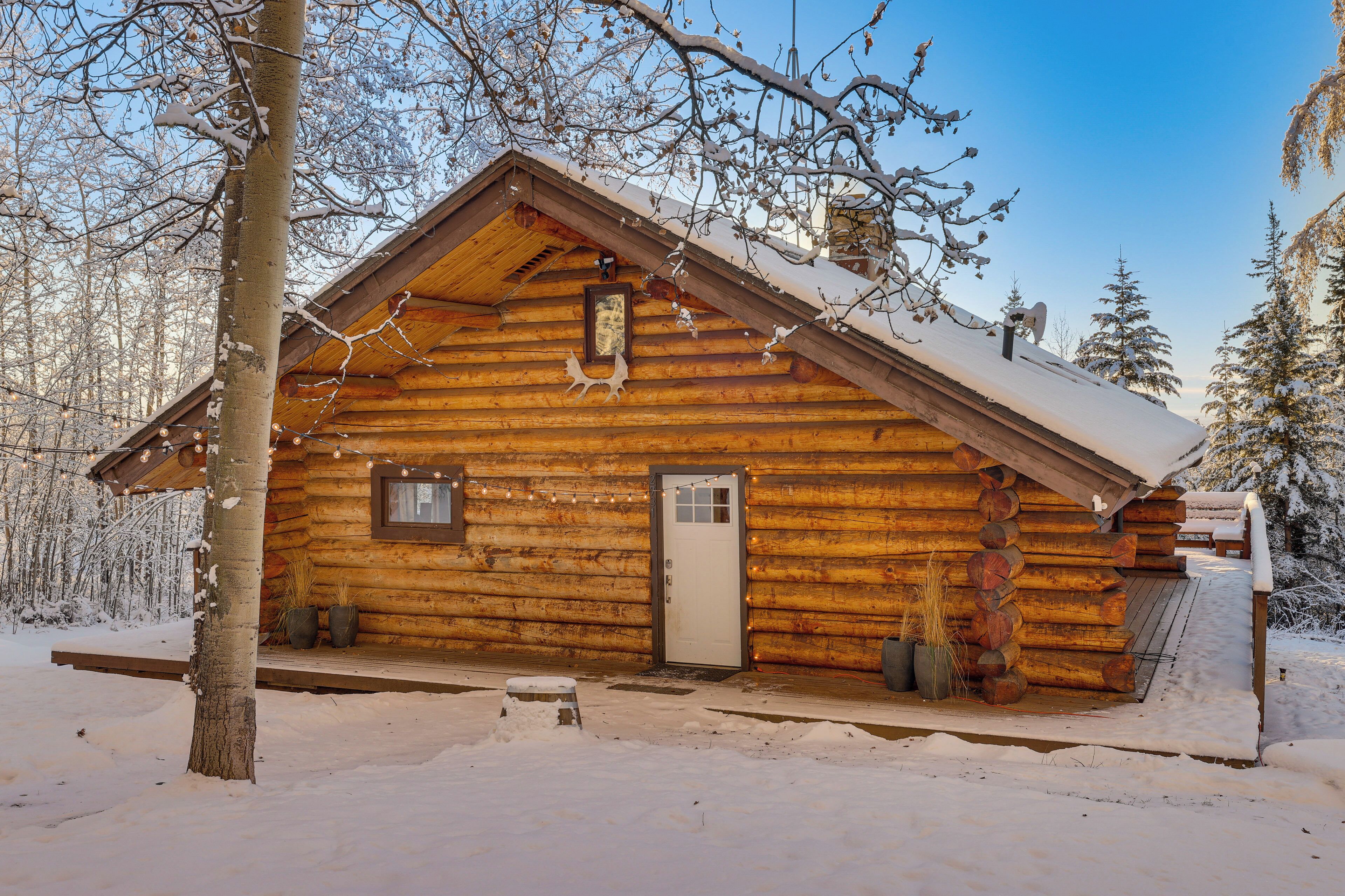 A log cabin with a wooden exterior, a front door, and a small porch area.