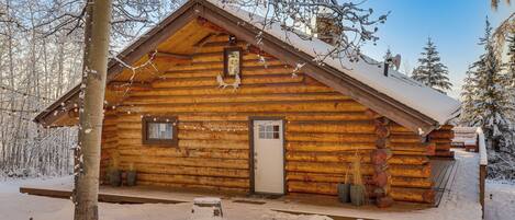 A log cabin with a wooden exterior, a front door, and a small porch area.