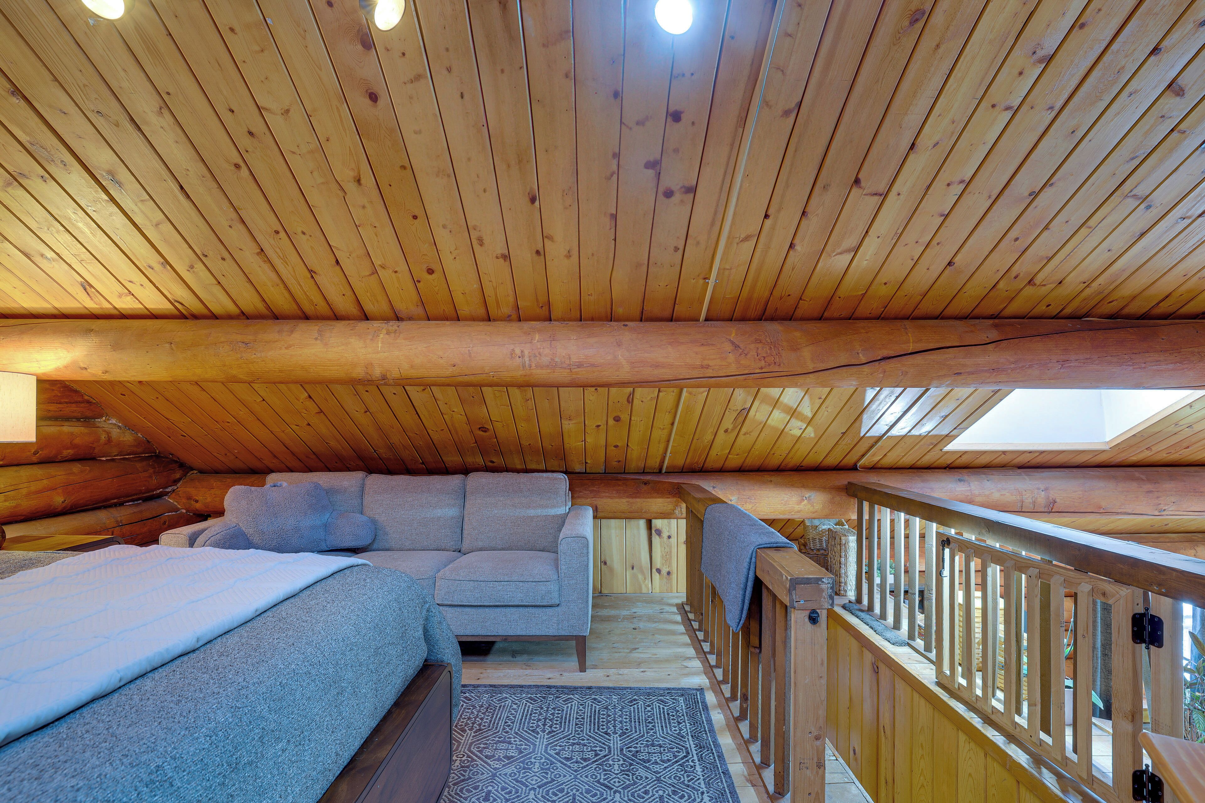 Une chambre confortable située sous les toits, avec un plafond en bois, un canapé, un lit et une vue sur l’extérieur.