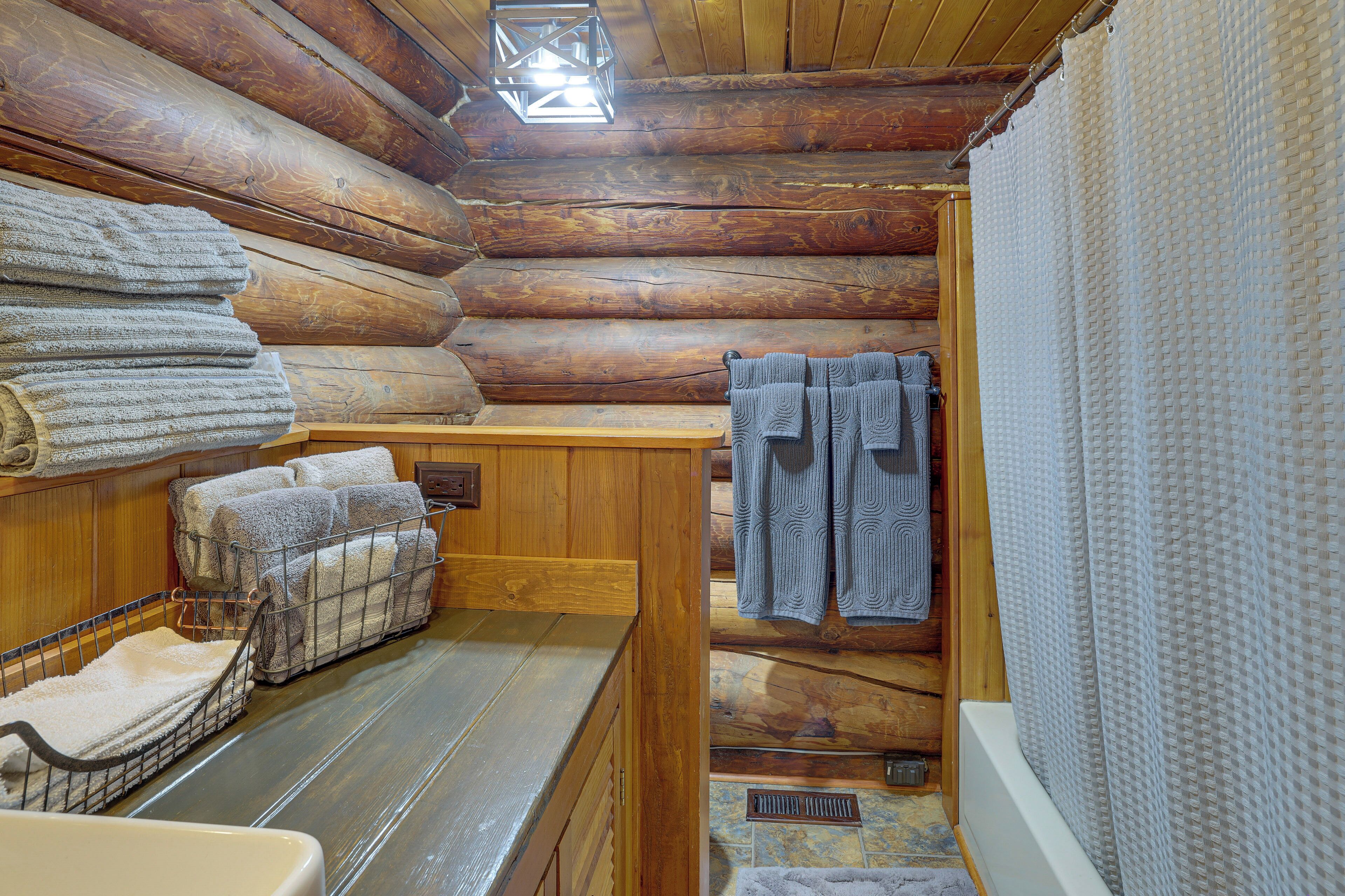A log cabin bathroom with wooden walls, a wooden bench, and towels.