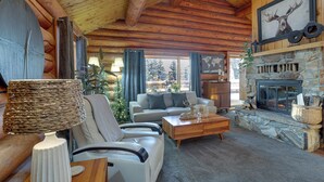 A cozy log cabin interior with a stone fireplace, a sofa, a coffee table, and a lamp. - Explore Fairbanks! Authentic Log Cabin w/ Views (Fairbanks)