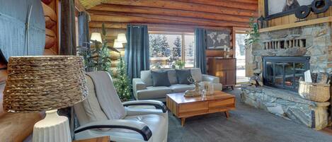 A cozy log cabin interior with a stone fireplace, a sofa, a coffee table, and a lamp.