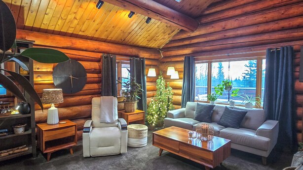 A log cabin interior with a cozy living area, including a sofa, armchair, coffee table, and a small side table with a lamp. - Explore Fairbanks! Authentic Log Cabin w/ Views (Fairbanks)