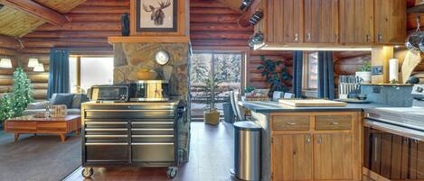 A log cabin interior with a kitchen, dining area, and a visible Christmas tree.