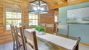 Une table à manger en bois, des chaises, un luminaire suspendu et un tableau au mur.