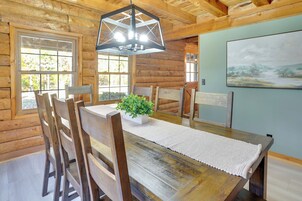 Una mesa de comedor de madera con sillas, una lámpara colgante y un cuadro en la pared.