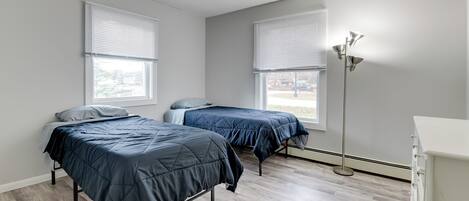 A bedroom with two beds, a floor lamp, and a dresser.