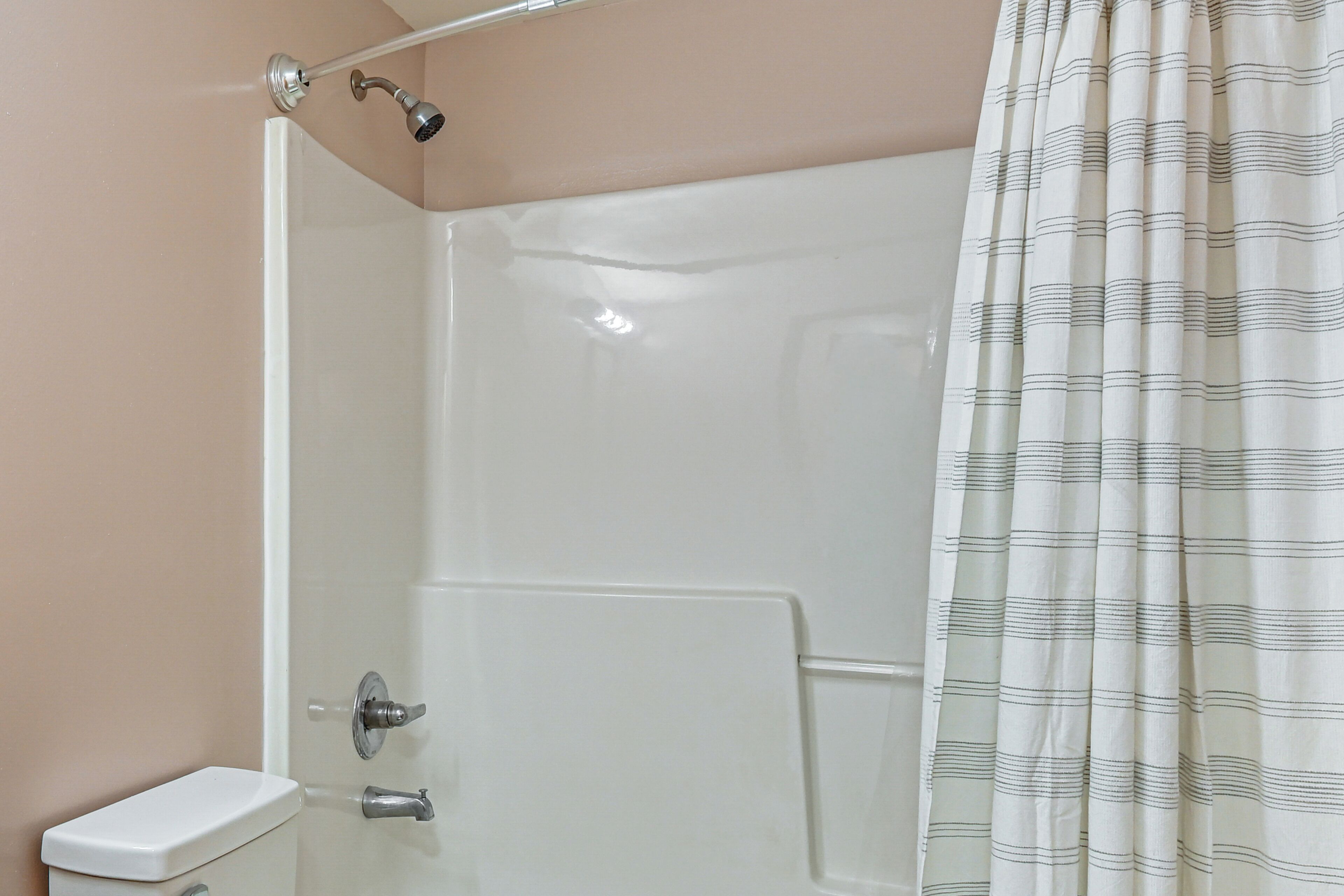 A shower with a glass door, a toilet, and a striped shower curtain.