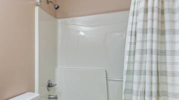 A shower with a glass door, a toilet, and a striped shower curtain.