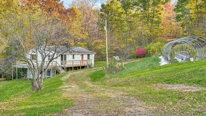 A house with a porch, surrounded by trees with autumn foliage. - Dirt Road Digs - Quiet Home in Lakeville! (Lakeville)