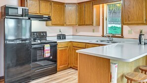 A kitchen with wooden cabinets, a stainless steel refrigerator, a microwave, a toaster, and a sink. - Dirt Road Digs - Quiet Home in Lakeville! (Lakeville)