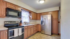 A kitchen with wooden cabinets, stainless steel appliances, and a tiled floor. - 15 Mi to Cochran's Ski Area: Cozy Home w/ Yard! (Essex Junction)