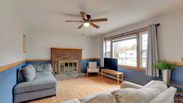 A living room with a fireplace, two sofas, a TV, and a ceiling fan. - 15 Mi to Cochran's Ski Area: Cozy Home w/ Yard! (Essex Junction)