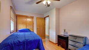 A bedroom with two beds, wooden doors, a dresser, and a ceiling fan. - 15 Mi to Cochran's Ski Area: Cozy Home w/ Yard! (Essex Junction)
