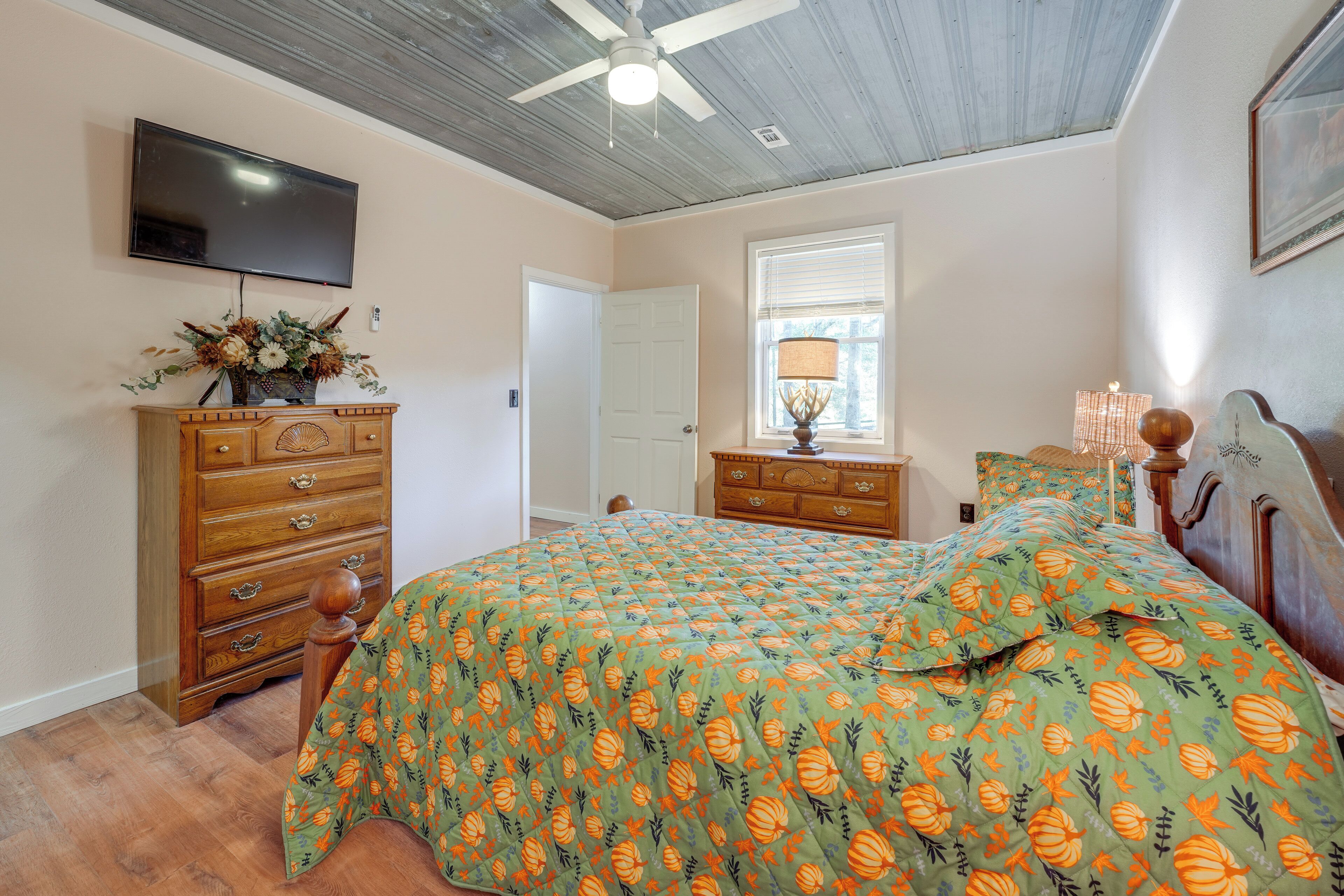 Ein Schlafzimmer mit einem Bett, einer Holzkommode und einem Fernseher an der Wand.