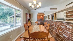 Comedor con pared de ladrillo, una lámpara de araña y vistas al exterior.