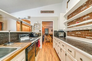 Una cocina con pared de ladrillo, armarios de madera y un reloj.