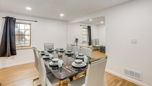 A dining area with a table set for four, white walls, and a window with curtains. - Updated Getaway w/ Sauna & Yard in Bloomsbury! (Bloomsbury)