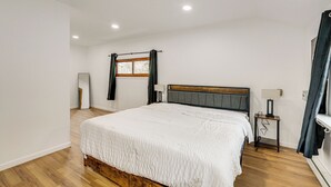 A bedroom with a wooden bed, a nightstand, a window with curtains, and a mirror. - Updated Getaway w/ Sauna & Yard in Bloomsbury! (Bloomsbury)