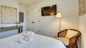 A bedroom with a bed, a wooden chair, a TV mounted on the wall, and a large framed artwork. - Coastal Convenience! Mt Pleasant Gem 2 Mi to Ocean (Mount Pleasant)