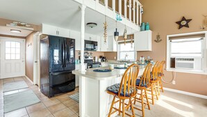 Una cocina con una isla central, muebles blancos y un refrigerador negro.