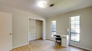 A spacious room with hardwood flooring, a desk, a chair, and a walk-in closet.