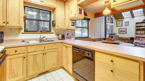 A kitchen with wooden cabinets, a dishwasher, a sink, and a window. - 1 Mi to Skiing! Cabin Hideaway on June Lake Loop (June Lake)