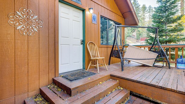 A wooden cabin with a porch, a swing chair, and a door with a sign above it. - 1 Mi to Skiing! Cabin Hideaway on June Lake Loop (June Lake)
