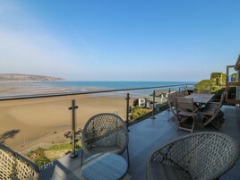 Balcón con mobiliario de mimbre con vista a una playa y al océano.