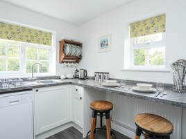 Una cocina moderna con armarios blancos, encimera de granito y dos taburetes de madera.