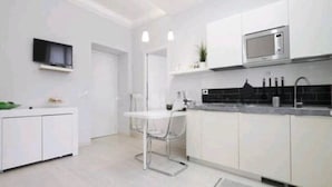 A modern kitchen with white cabinetry, a black countertop, and a built-in microwave.
