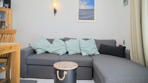 Ein modernes Wohnzimmer mit einem grauen Sofa, einem Holztisch und einem gerahmten Bild an der Wand.