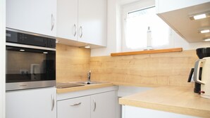 Eine moderne Küche mit weißen Schränken, einem Edelstahlbackofen, einer Holz Arbeitsplatte und einem Fenster über der Spüle.