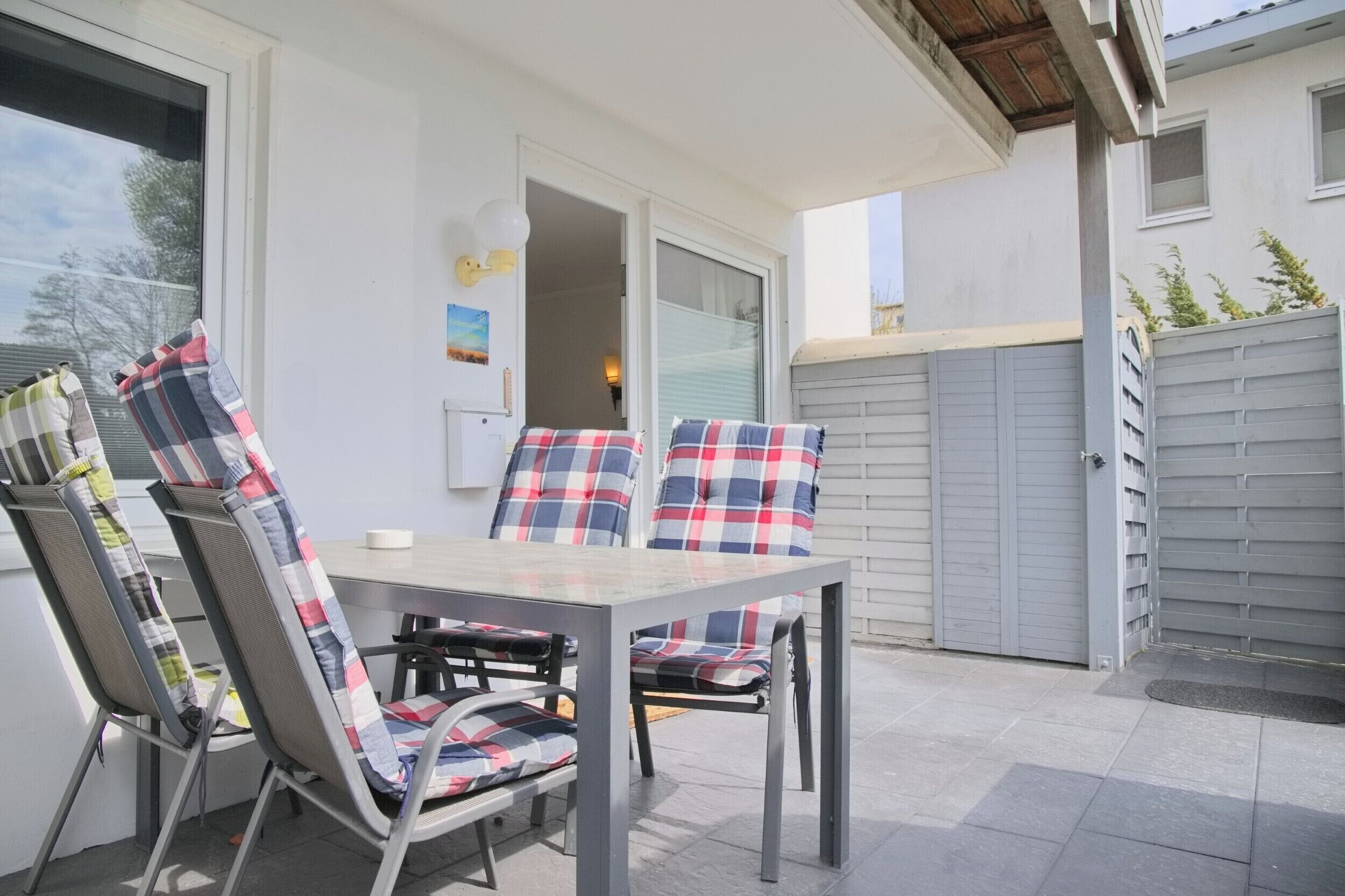 An outdoor patio with a table and chairs, a sliding glass door, and a grey garage door.