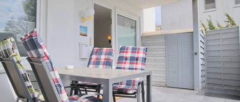 An outdoor patio with a table and chairs, a sliding glass door, and a grey garage door.