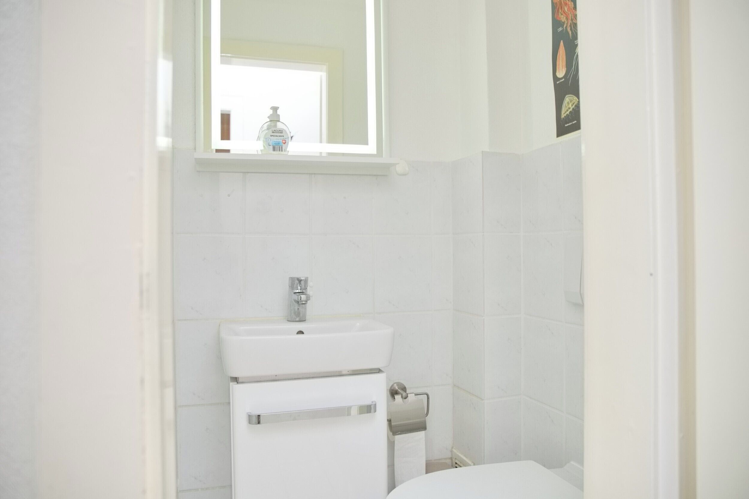 Een badkamer met een wit wastafelmeubel, een spiegel erboven en een toilet.