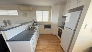 A modern kitchen with white cabinets, a stainless steel refrigerator, and a microwave. - Seaviews at Stansbury - Modern and spacious! Off Peak special available! (Stansbury)