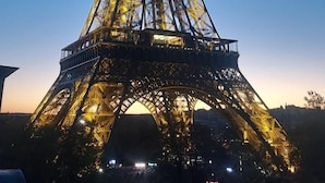 La Tour Eiffel au coucher du soleil, avec sa structure complexe en treillis de fer et le panorama urbain qui l’entoure.