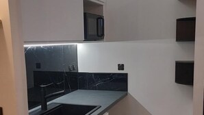 Une cuisine compacte équipée d’un lave-linge, d’un four à micro-ondes et d’un four encastré.