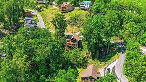 A remote, forested area with several houses, including a large cabin with a deck and a smaller house with a green roof. - 5BR Gatlinburg Family Getaway with Views, Hot Tub & Game Room in Chalet Village (Gatlinburg)
