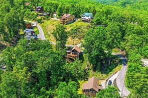 Eine abgelegene, bewaldete Gegend mit mehreren Häusern, darunter eine große Blockhütte mit einer Terrasse und ein kleineres Haus mit einem grünen Dach.