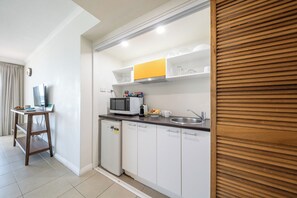 A compact kitchenette with a microwave, coffee maker, and a small refrigerator. - Perfect Coastal Escape – Spa Bath, Ocean Views & Prime Location (Airlie Beach)