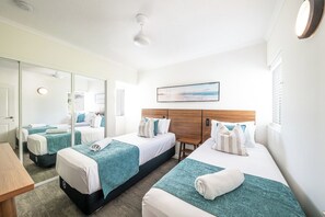 A hotel room with two beds, a large mirror, and a view of the sea. - Port Views On Airlie Premier (Airlie Beach)
