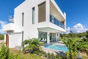 A modern two-story house with a swimming pool, large windows, and a balcony. - NEW Villa Golf Course views, Roof Top Hot Tub, near Grace Bay Beach- Gabriella 2 (Grace Bay)