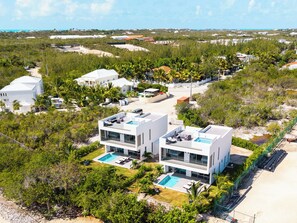 A modern two-story building with a rooftop pool and a large rectangular pool in the front yard. - NEW Villa Golf Course views, Roof Top Hot Tub, near Grace Bay Beach- Gabriella 2 (Grace Bay)