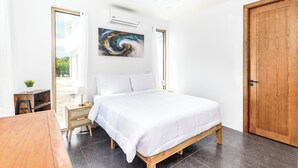 Een slaapkamer met een bed, een houten deur, een plafondventilator en een raam.