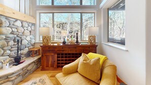 Ein gemütliches Zimmer mit Steinwand, Holzmöbeln und großen Fenstern.