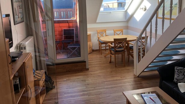 En hyggelig loftlejlighed med spiseplads, trappe og udsigt over bybilledet.