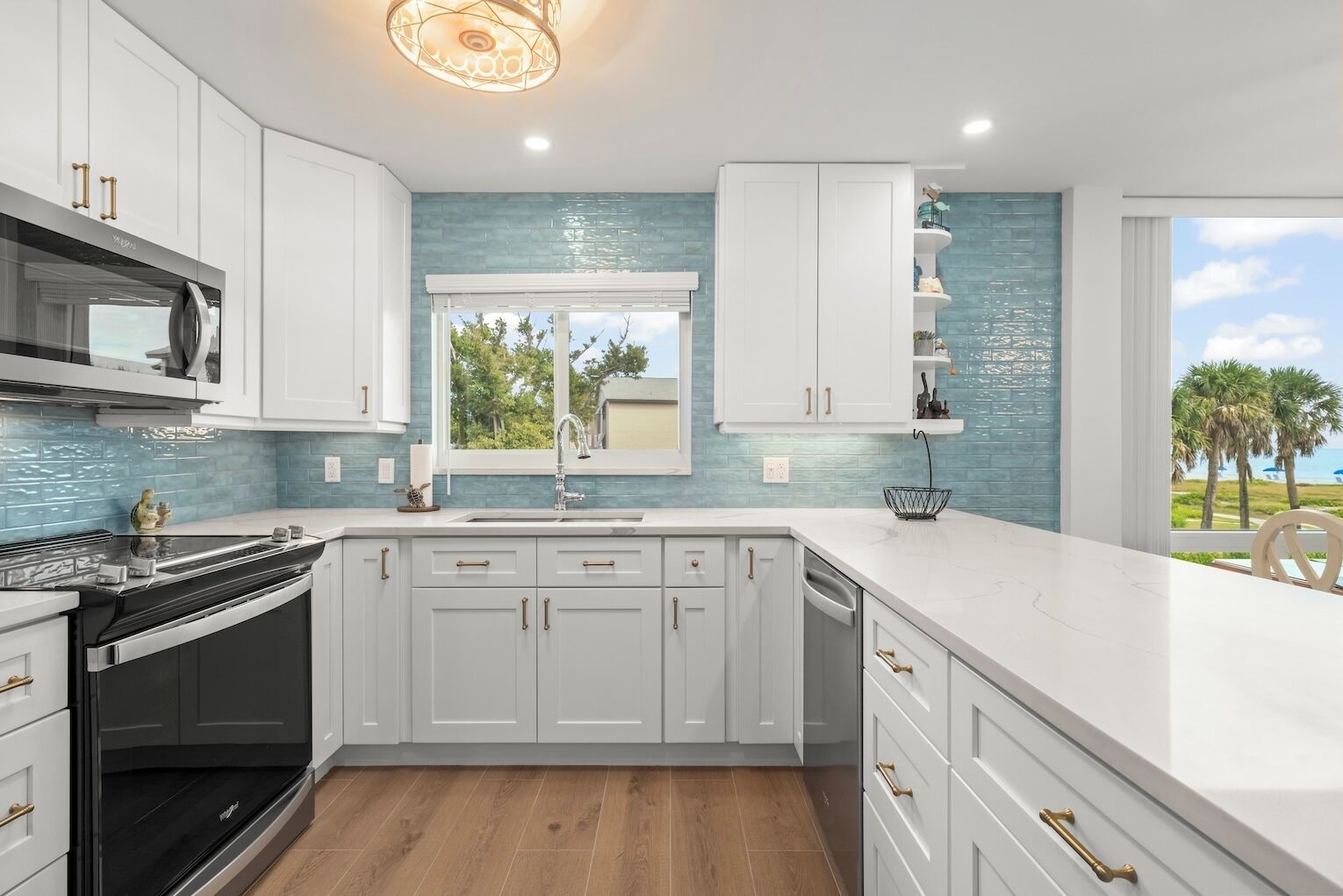 A modern kitchen with white cabinets, a black stove, and a view of the outdoors.
